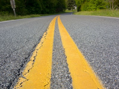 Double solid yellow line markers on the center of a road.