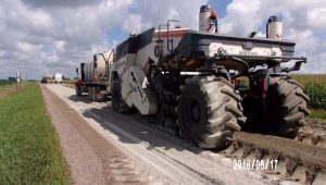 Truck incorporating cement into road materials on rural road. 